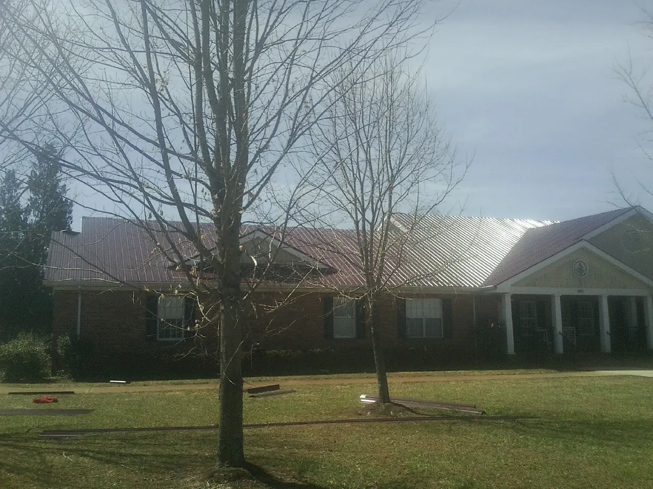 Red metal roof on a brick building seen from the front lawn in Kingsbury