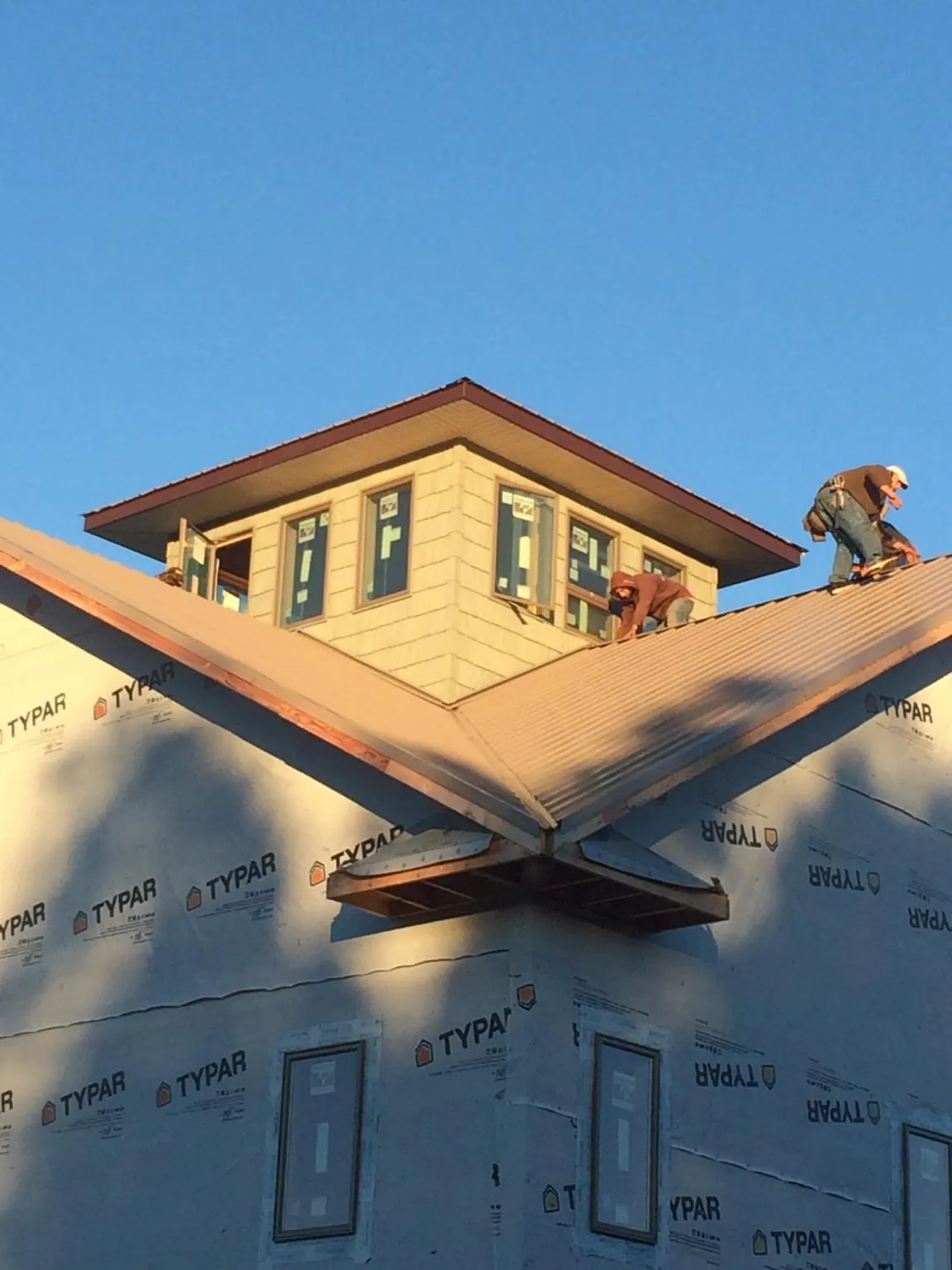 Roofers working around a rooftop cupola on a new metal roof at sunset — Roof Waterproofing in Kingsbury by Roofing Brothers